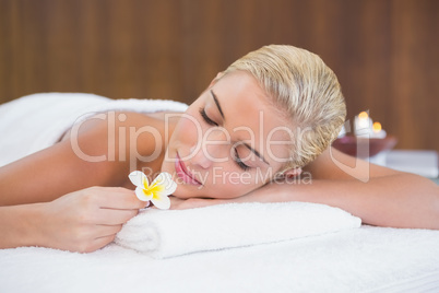 Woman holding flower on massage table at spa center