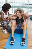 Personal trainer working with client on exercise mat