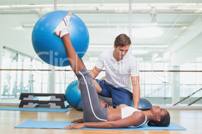Personal trainer working with client holding exercise ball