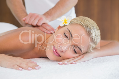 Woman receiving back massage at spa center