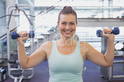 Fit brunette holding blue dumbbells