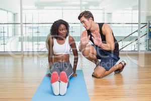 Personal trainer working with client on exercise mat