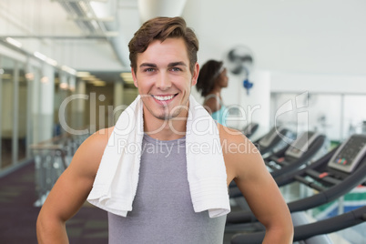 Handsome man smiling at camera beside treadmills