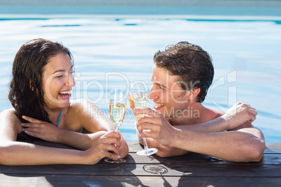 Cheerful couple toasting champagne in swimming pool