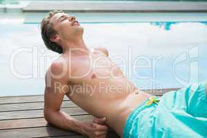 Man lying by the swimming pool on a sunny day