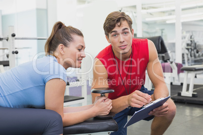 Personal trainer working with client holding dumbbell