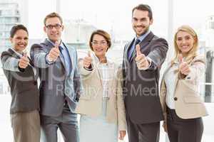 Business people gesturing thumbs up in office