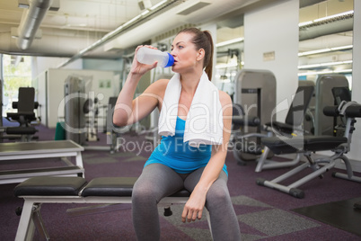 Fit brunette drinking from sports bottle