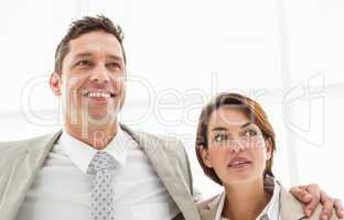 Business couple looking up in office