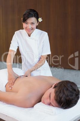 Female masseur massaging mans back at spa center