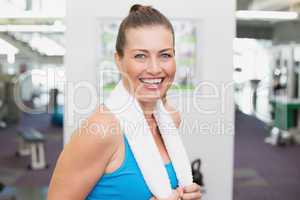 Fit brunette smiling at camera in fitness studio