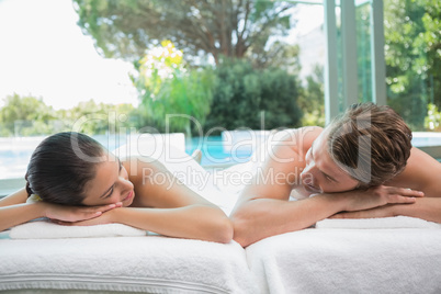 Couple lying on massage table at spa center