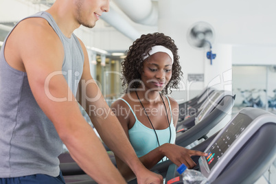 Fit woman on treadmill talking to personal trainer