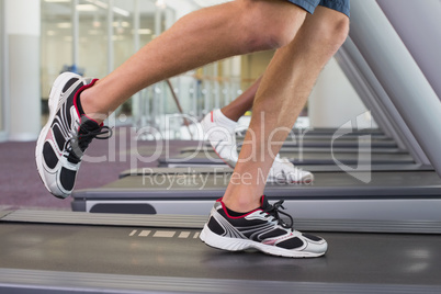 Fit man and woman running on treadmill