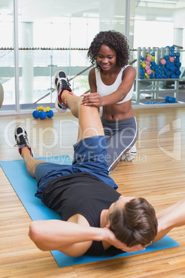 Personal trainer working with client on exercise mat