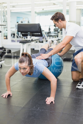 Personal trainer working with client on exercise ball