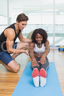 Personal trainer working with client on exercise mat