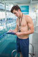 Swimming instructor writing on clipboard by the pool