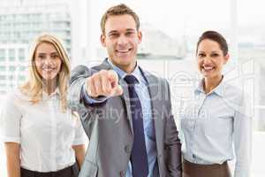 Businessman pointing at you with colleagues in office