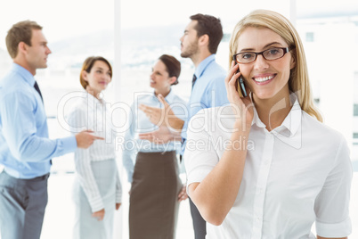 Businesswoman using mobile phone with colleagues behind