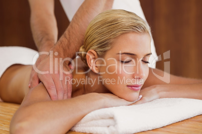 Woman receiving shoulder massage at spa center