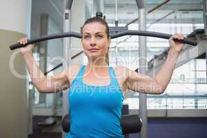 Fit brunette using weights machine for arms