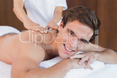 Handsome man receiving shoulder massage at spa center