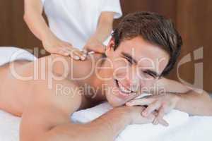 Handsome man receiving shoulder massage at spa center