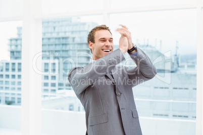 Businessman clapping hands in office