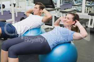 Couple doing sit ups on exercise balls