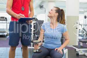 Personal trainer working with client holding dumbbell