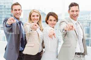 Happy business people pointing at you in office