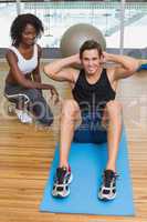 Personal trainer working with client on exercise mat