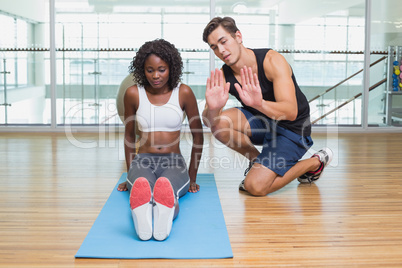 Personal trainer working with client on exercise mat