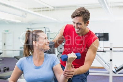 Personal trainer helping client lift dumbbells