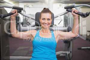 Fit brunette using weights machine for arms