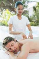 Handsome man receiving back massage at spa center