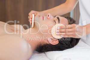 Man receiving facial massage at spa center