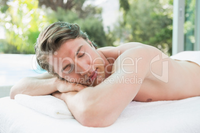 Handsome man lying on massage table at spa center