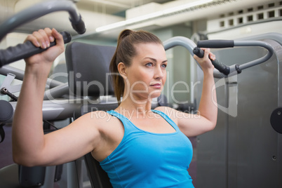 Fit brunette using weights machine for arms