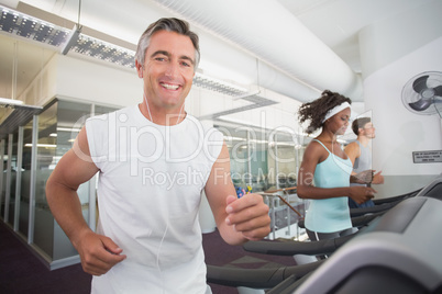 Fit man running on treadmill listening to music