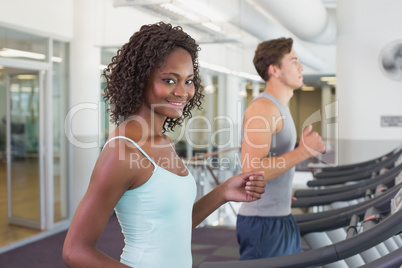 Fit woman smiling at camera on treadmill