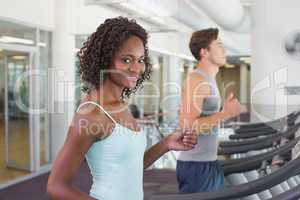 Fit woman smiling at camera on treadmill