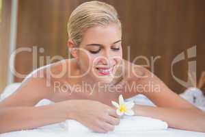 Woman holding flower on massage table at spa center
