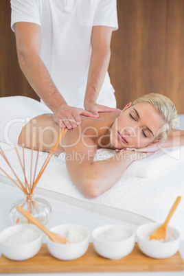 Woman receiving back massage at spa center