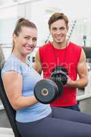 Personal trainer working with client holding dumbbell