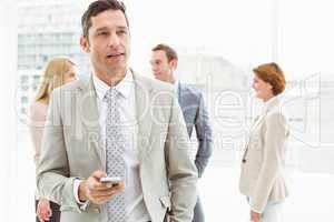 Businessman text messaging with colleagues in meeting behind