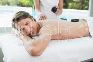 Handsome man receiving stone massage at spa center