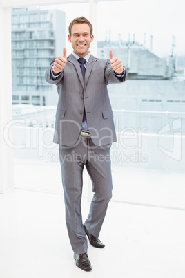 Businessman gesturing thumbs up in office Businessman gesturing thumbs up in office