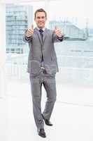 Businessman gesturing thumbs up in office